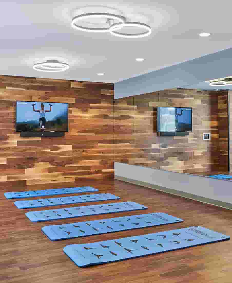 Yoga Room with large mirrors, wood panelled wall, and mounted TV for fitness on demand