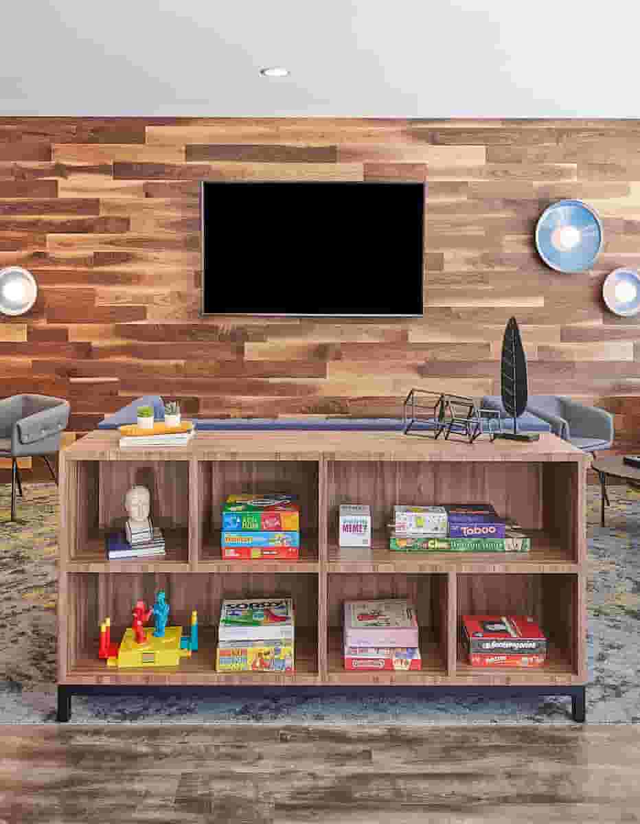 Board games on a bookshelf with TV are behind
