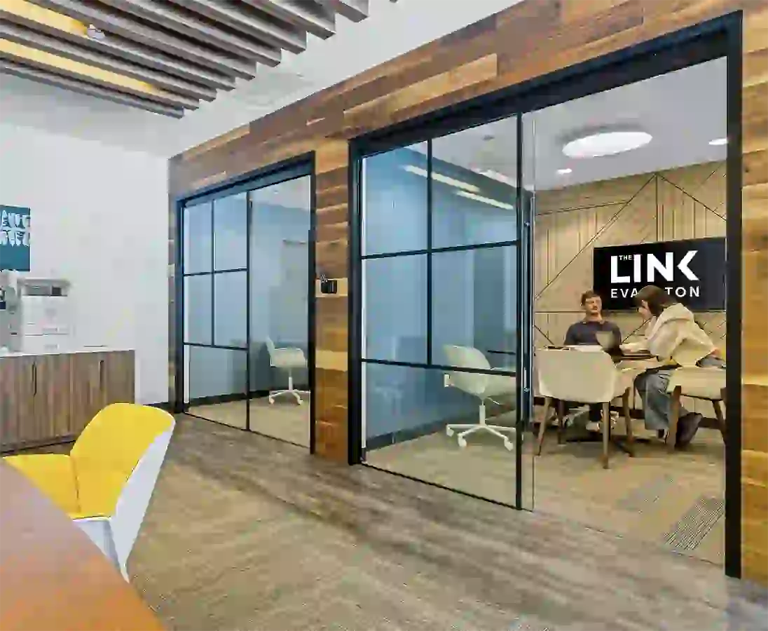 Collaboration desks with private meeting rooms in the background at The Link Evanston